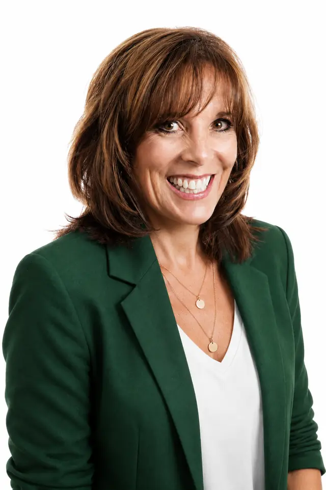 Portrait of Diane Beaumont, smiling, wearing a forest-green blazer